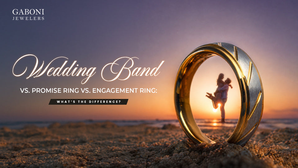 Gaboni Jewelers blog banner titled Wedding Band vs Promise Ring vs Engagement Ring framing a couple at the beach through a gold tungsten ring.