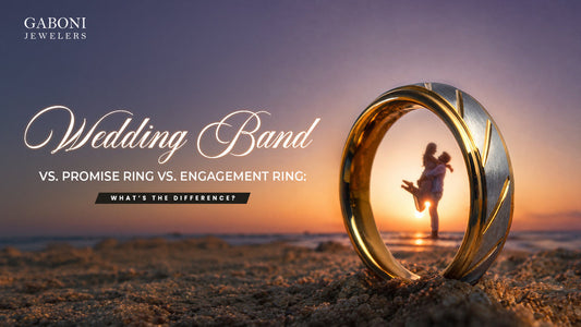 Gaboni Jewelers blog banner titled Wedding Band vs Promise Ring vs Engagement Ring framing a couple at the beach through a gold tungsten ring.